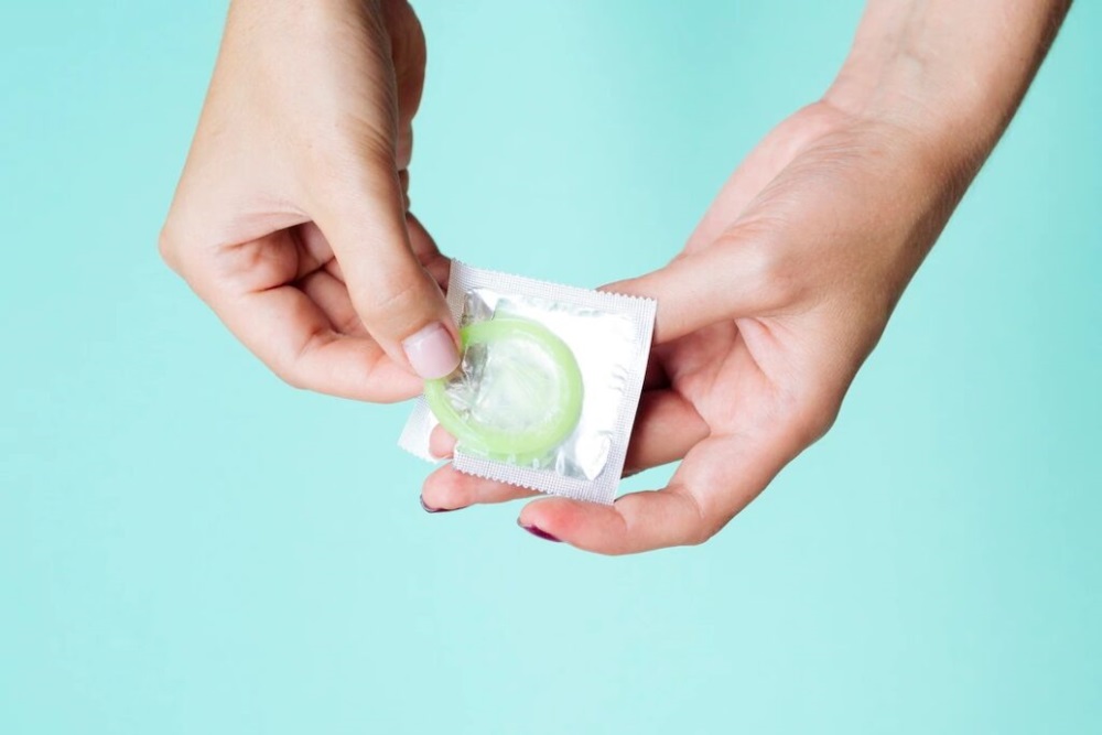 женские руки распаковывают презерватив